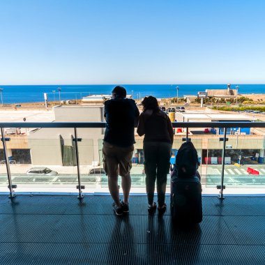 açık teras havaalanında bekleyen yolcular silüeti