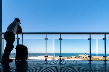 açık teras havaalanında bekleyen yolcular silüeti