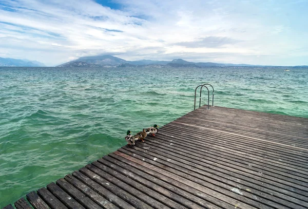 Dřevěné molo a zamračená obloha nad jezero Garda - Itálie — Stock fotografie