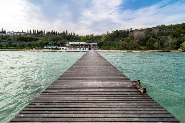 Cais de madeira e céu nublado sobre o lago Garda - Itália — Fotografia de Stock