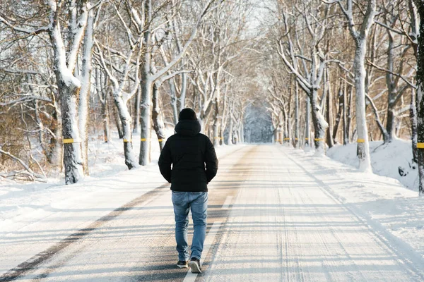 Man walks alone on snowy road. Travel alone concept. Faceless.