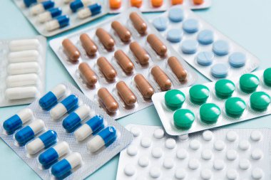 Farklı tabletler, haplar, kapsül ilaçları mavi arka planda su toplayan paketler. Tedavi kavramı, tıp. Seçici odak.