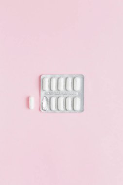Pembe arka planda ilaç içeren beyaz kapsüller. Kadın Sağlığı. Doğum kontrol hapları. İlaç almaya başla..