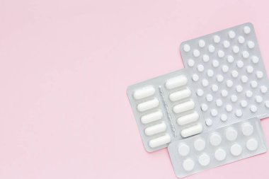 Pembe arka planda ilaç içeren beyaz haplar ve kapsüller. Kadın Sağlığı. Hastalık önleme. Boşluğu kopyala.