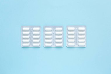 Mavi arka planda beyaz hap paketleri, üst manzara. Farklı ilaçlar, haplar, ilaç kapsülleri.