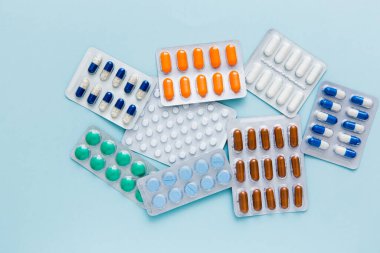 Farklı tabletler, haplar, kapsül ilaçları mavi arka planda su toplayan paketler. Sağlık hizmeti konsepti. Sakinleştirici..