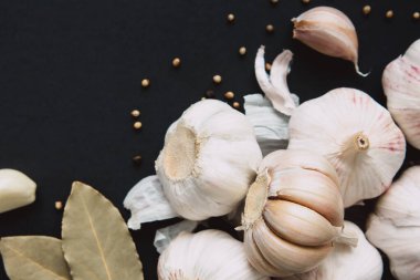 Siyah arka planda baharat, biber ve defne yaprağıyla sarımsak soğanı. Doğal antibiyotikler. Sağlıklı gıda konsepti.