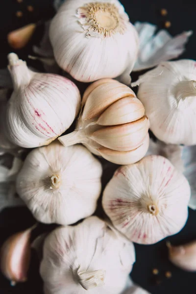 Garlic bulbs on black background, close-up. Organic garlic top view. Food background. Vertical photo. Selective focus.