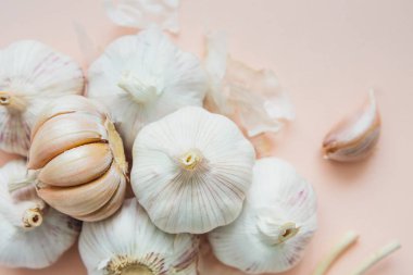 Pembe arka planda sarımsak soğanları, yakın plan. Organik sarımsaklı üst manzara. Yemek arkaplanı. Seçici odak.