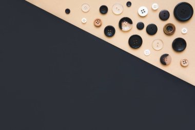 Dikiş ve el yapımı konsept. Bej ve siyah arka planda farklı boyutlarda birçok yuvarlak dikiş düğmeleri, üst görünüm. İğne işi ve hobi geçmişi.