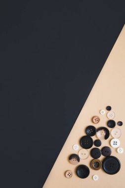 Dikiş ve el yapımı konsept. Bej ve siyah arka planda farklı boyutlarda birçok yuvarlak dikiş düğmeleri, üst görünüm. İğne işi ve hobi geçmişi.
