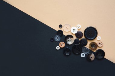 Dikiş ve el yapımı konsept. Bej ve siyah arka planda farklı boyutlarda birçok yuvarlak dikiş düğmeleri, üst görünüm. İğne işi ve hobi geçmişi.