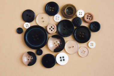 Bej arka planda farklı boyutlarda siyah yuvarlak düğmeler, üst manzara. Dikiş ve dikiş konsepti.