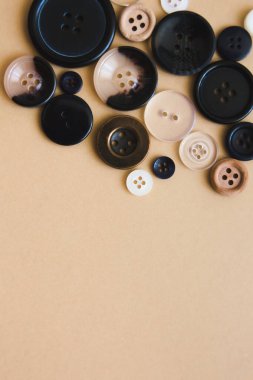 Bej arka planda farklı boyutlarda siyah yuvarlak düğmeler, üst manzara. Dikiş ve dikiş konsepti. Boşluğu kopyala.