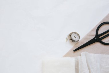 Beyaz arka planda doğal kumaş, makas ve mezura örnekleri. Kesme ve dikiş konsepti. Boşluğu kopyala.