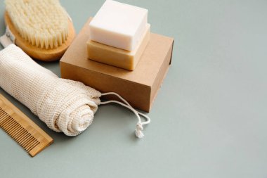 Sıfır atık konsepti, çevre dostu yaşam tarzı, plastik yok. Doğal banyo aksesuarları: organik sabun, doğal fırça, saç tarağı, yeşil arka planda yeniden kullanılabilir pamuk torbaları..