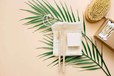 Çevre dostu banyo aksesuarları: bambu diş fırçaları, bambu kulak çubukları, organik sabun, bej arka planda yeniden kullanılabilir pamuk torbaları. Sorumlu tüketim kavramı.