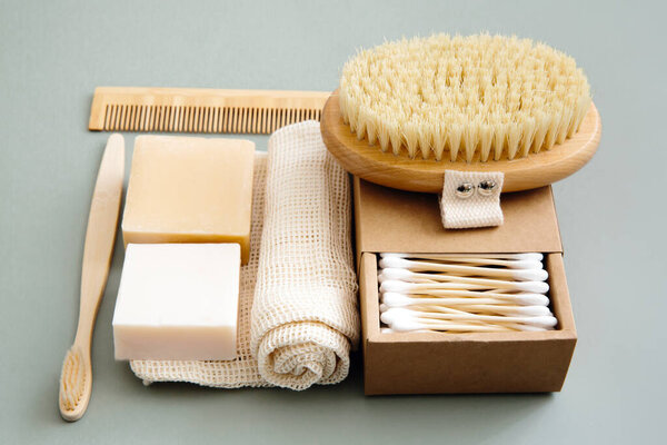 Zero waste concept, eco-friendly lifestyle, no plastic. Natural bathroom accessories: organic soap, natural brush, bamboo ear sticks, reusable cotton bags on green background.
