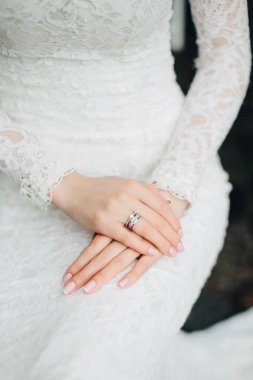 Güzel dantelli beyaz elbiseli gelin, yüzüklü ellerin yakın çekimi. Düğünden önce heyecan.