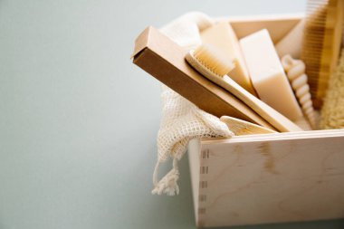Natural bathroom accessories: Bamboo toothbrush, organic soap on green background, close up. Zero waste concept, eco-friendly lifestyle, plastic free.