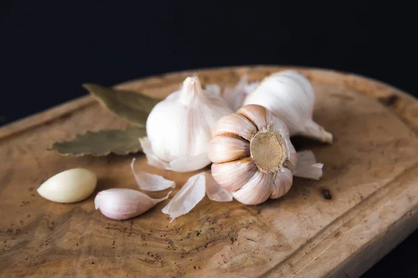 Garlic bulbs on wooden board, on black background. Natural antibiotic. Growing vegetables home, farming.