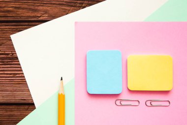 Renkli kağıtlar, çıkartmalar, kalemler ve yazı malzemeleriyle ahşap ofis masası. Üst görünüm, boşluğu kopyala. Okula geri dön..