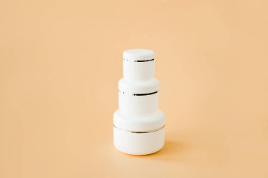 Beyaz, yuvarlak kozmetik kaplar ve bej arka planda şişeler. Yüz bakımı kozmetik seti. Boşluğu kopyala.