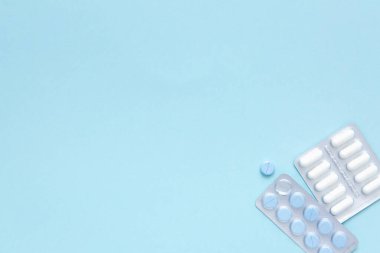 Mavi arka planda beyaz ve mavi hapların kabarcıkları, üst manzara. Farklı ilaç ürünleri, haplar, ilaç kapsülleri. Tedavi konsepti. Ağrı kesici..