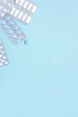 Mavi arka planda beyaz ve mavi hapların kabarcıkları, üst manzara. Farklı ilaç ürünleri, haplar, ilaç kapsülleri. Tedavi konsepti. Ağrı kesici. Dikey fotoğraf.
