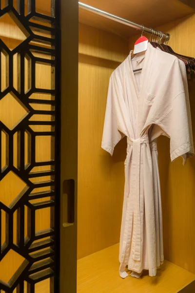 Белый халат с деревянными вешалками в шкафу — стоковое фото