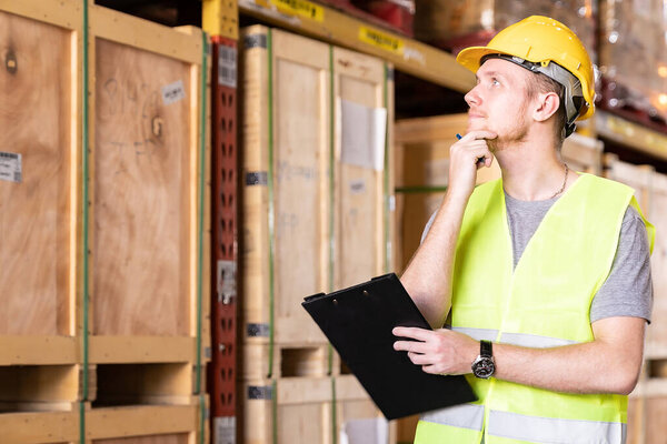 Portrait white caucasian warehouse worker stand with clipboard and pen for inventory check in large warehouse distribution center. Reopening traditional business warehouse and logistic concept