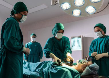 Cerrah doktor ve hemşire hasta ameliyathanede ameliyat sırasında ani kalp krizi geçirirken defibrilatör kullanıyor. Sağlık hizmetleri cerrahi konsepti.
