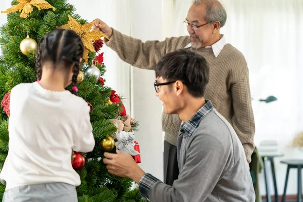 クリスマスツリーを飾る多世代のアジアの家族 お母さんお父さんの娘の女の子と祖父は メリークリスマスとハッピーホリデーの季節の挨拶のためのクリスマスツリーの準備を飾る — ストック写真