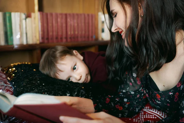 A young woman reads a book to a child. A mother teaches her little boy to read. Home-based education