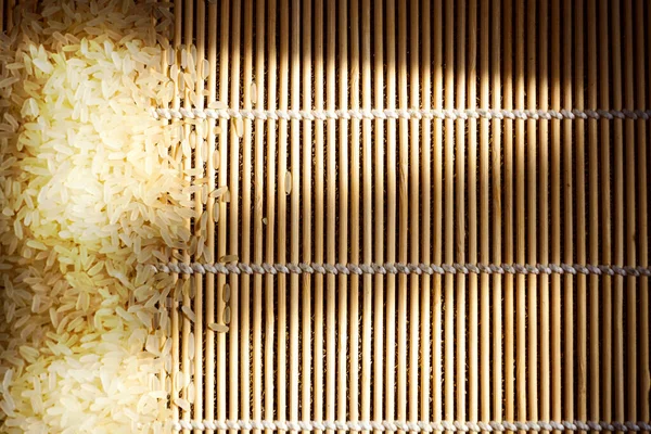 Smooth wooden surface sprinkled with white rice. Background with copy space for Chinese or Japanese cuisine menus.