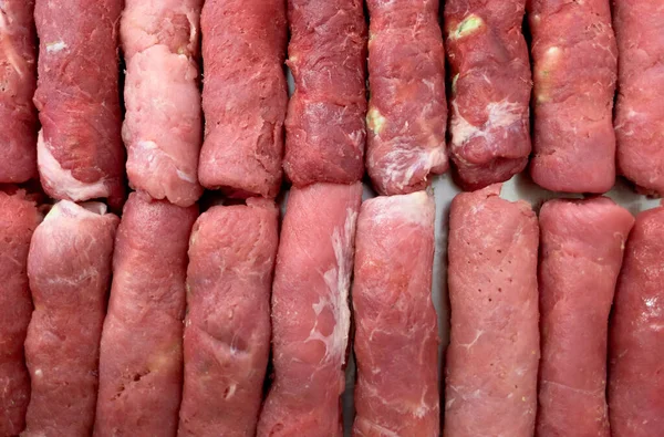Blanks of round meat sausages are stacked in a row. Cooking meat dishes for lunch. — Stock Photo, Image