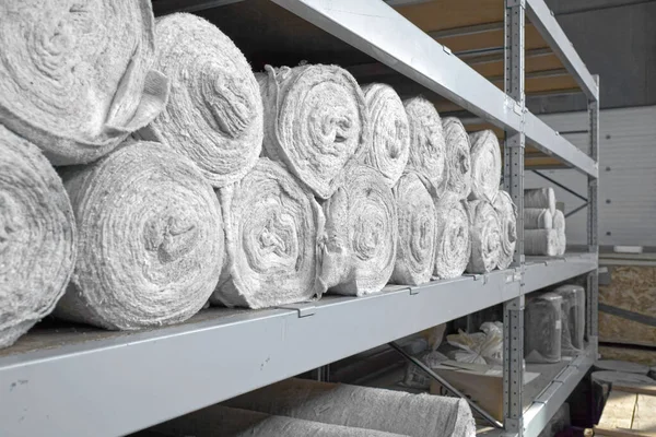 White non-woven fabric in rolls is on the shelves of the warehouse. Covering material. Textiles for the production of rags. Close-up with copy space