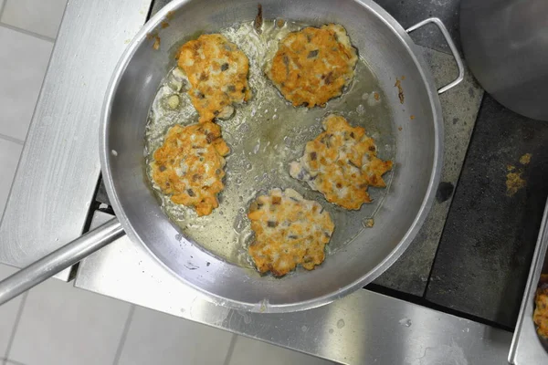 Cooking meat in batter on the stove in a fast food canteen. Fat and harmful high-calorie food is cooked in a frying pan. Top view