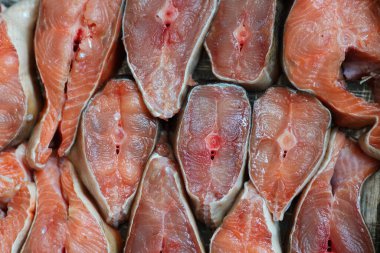 Dilimlenmiş kırmızı balık parçaları sıraya dizilir. Somon balığının soyut arkaplanı ya da yakın plan pembe somon balığı. Balık ürünleri için arkaplan