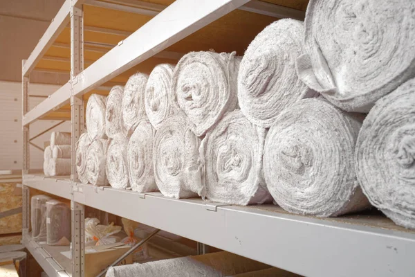 White non-woven fabric in rolls is on the shelves of the warehouse. Covering material. Textiles for the production of rags. Close-up with copy space
