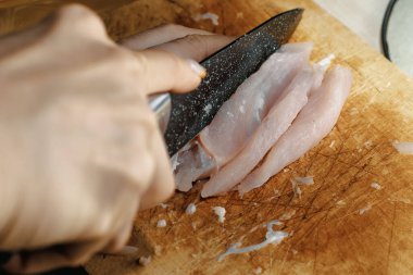 Şef et filetosunu ahşap bir kesim tahtasıyla büyük bir mutfak bıçağıyla parçalara ayırır. Et yemeği pişirme süreci yakın plan.