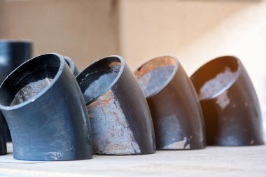 Gaz ve su tedariği için farklı çaplara sahip siyah metal borular ve adaptörler. Fotokopi alanı olan endüstriyel arka plan. Metal ürünleri için depolama