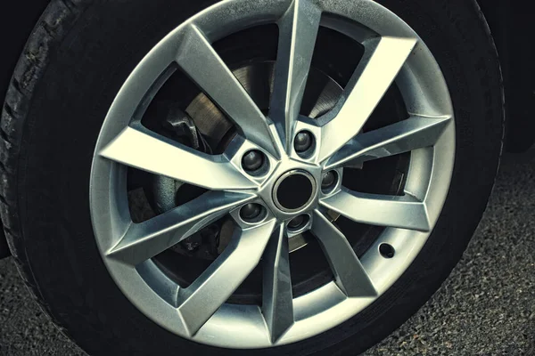 Nueva rueda de coche con rueda de aleación. Detalle del coche sobre un fondo de asfalto gris. — Foto de Stock