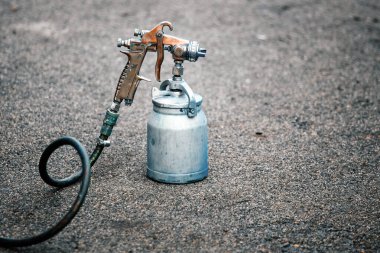 Asfaltta eski bir sprey tabanca duruyor. Endüstriyel resim teması. 