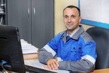 Masasında sandalyede oturan mutlu mühendis. Bir yapım işçisinin portresi