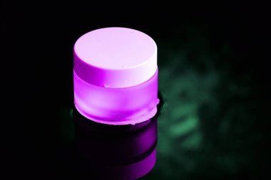 Beyaz kapaklı pembe cam bir kavanoz suyun içinde duruyor. Karanlık tema.