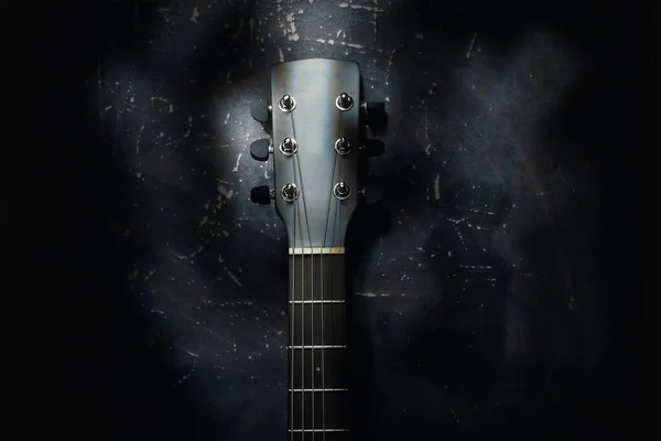 Egy akusztikus gitár áll a falnak egy sötét háttérrel szemben. Háttér — Stock Fotó