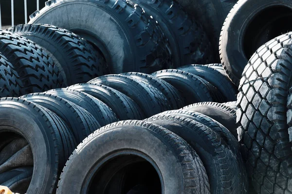 Recycling of car tires for trucks. Thats a lot of black bald rubber tires lying outside in an open warehouse.