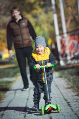 Küçük mutlu bir çocuk, bir sonbahar günü babasıyla parkta yürüyor.. 