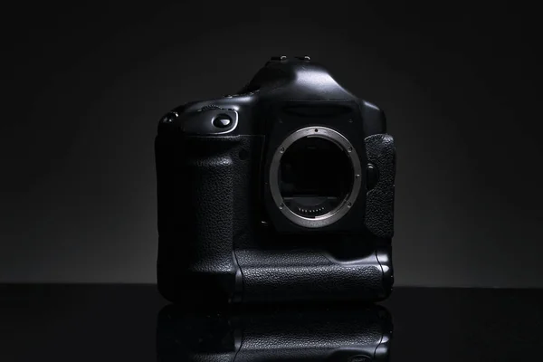 La carcasa masiva de una cámara SLR profesional sin una lente se apoya sobre un fondo negro. —  Fotos de Stock